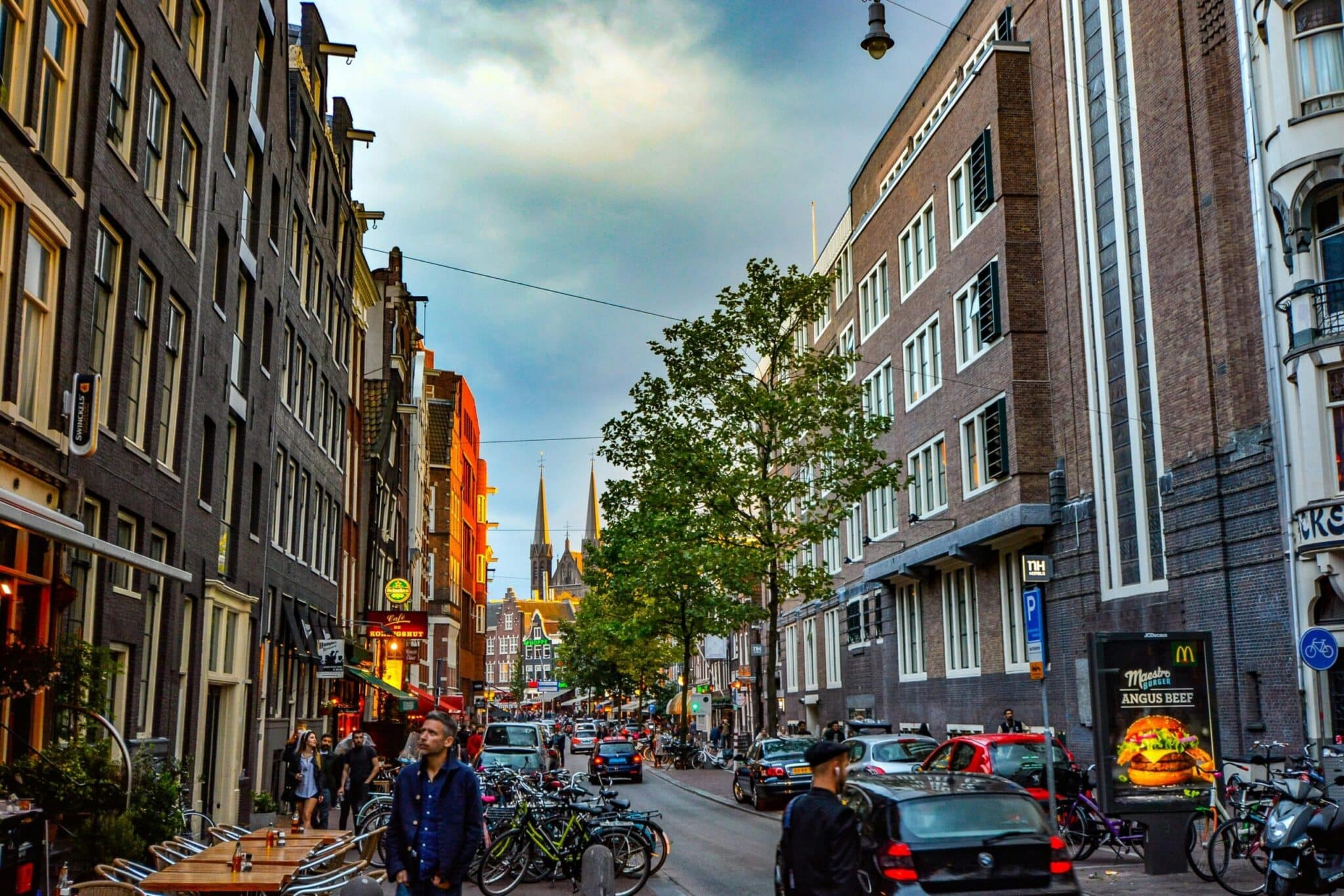 Lively Amsterdam street capturing architecture, bikes, and urban life at dusk, showcasing the city's unique charm.